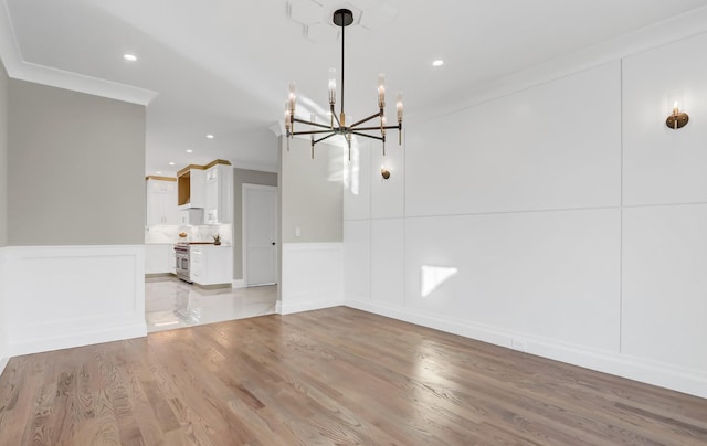 unfurnished dining area with an inviting chandelier, light hardwood / wood-style flooring, and ornamental molding