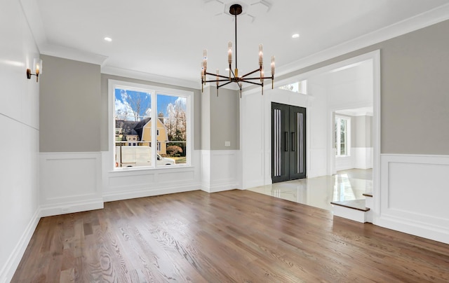 unfurnished dining area with hardwood / wood-style floors, an inviting chandelier, and ornamental molding