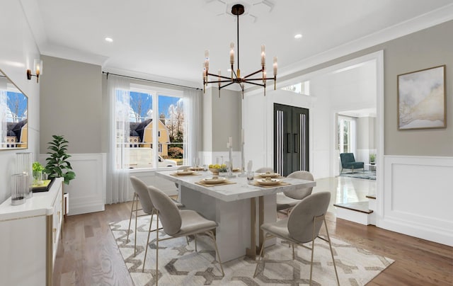 dining room featuring light hardwood / wood-style floors, crown molding, and a notable chandelier