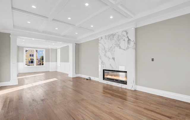 unfurnished living room featuring a high end fireplace, hardwood / wood-style floors, coffered ceiling, and beam ceiling