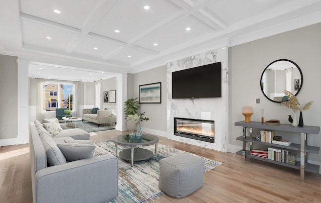 living room with beam ceiling, a fireplace, light hardwood / wood-style floors, and coffered ceiling