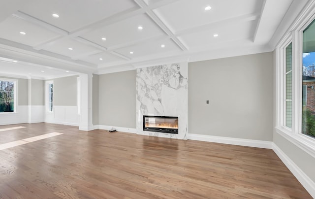 unfurnished living room with beam ceiling, a premium fireplace, light hardwood / wood-style floors, and coffered ceiling