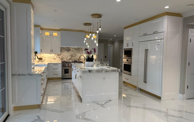 kitchen featuring light stone countertops, pendant lighting, high quality appliances, white cabinets, and a kitchen island