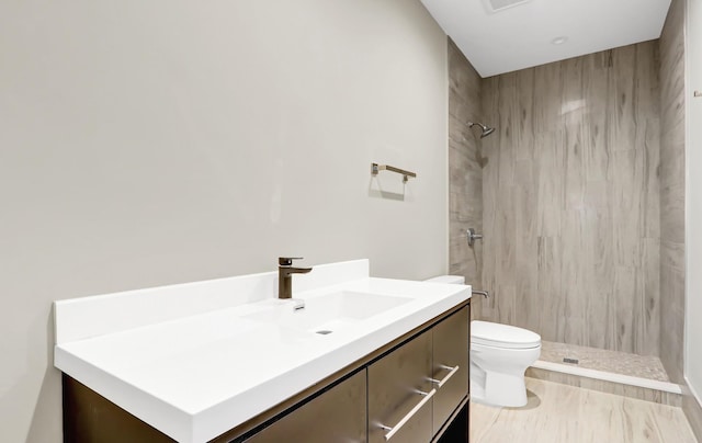 bathroom featuring toilet, vanity, and tiled shower