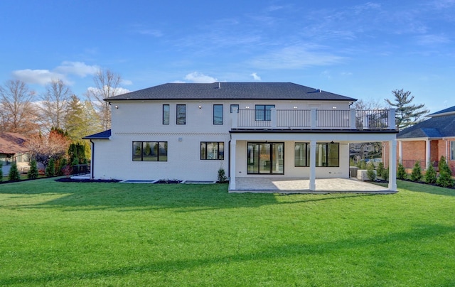 rear view of house with a lawn, a balcony, and a patio