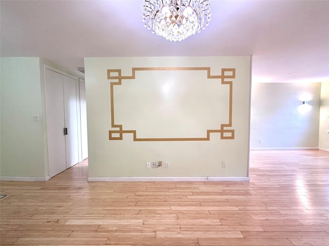 empty room featuring an inviting chandelier and light wood-type flooring