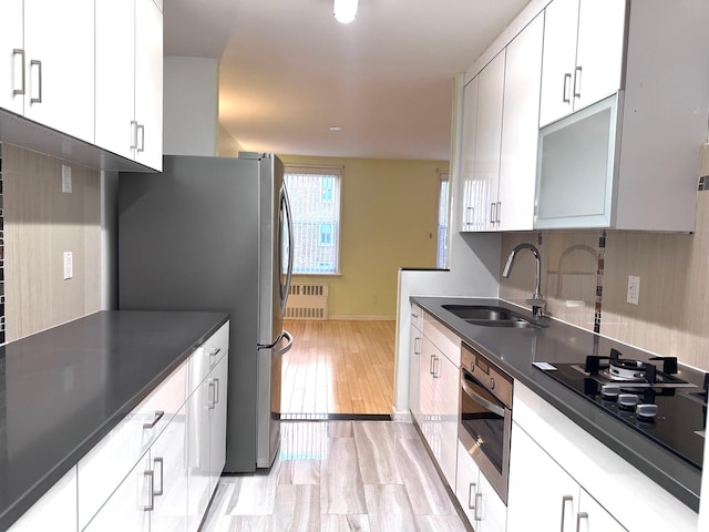 kitchen featuring white cabinets, radiator heating unit, and sink