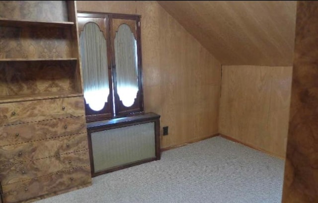 bonus room with radiator, light colored carpet, vaulted ceiling, wooden walls, and wooden ceiling