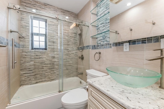 full bathroom with vanity, toilet, enclosed tub / shower combo, and tile walls
