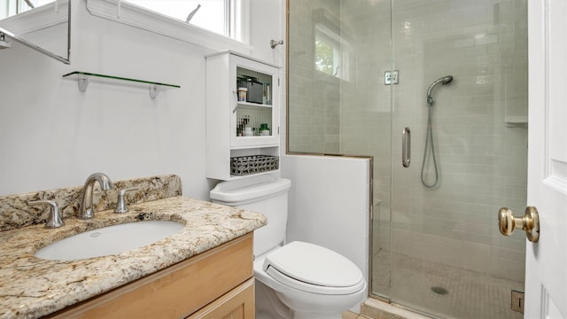 bathroom with a shower with shower door, vanity, and toilet