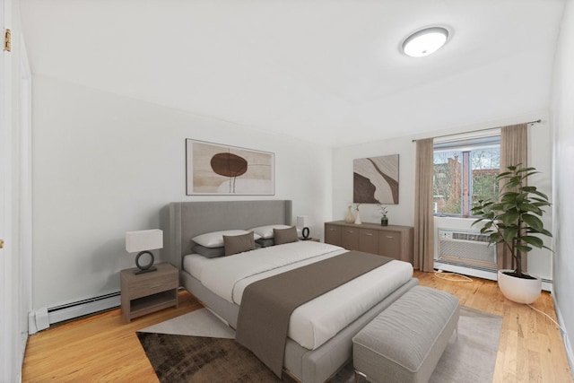 bedroom featuring light wood-type flooring and a baseboard heating unit