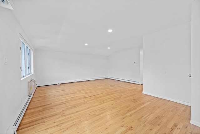 empty room featuring a baseboard heating unit and light wood-type flooring