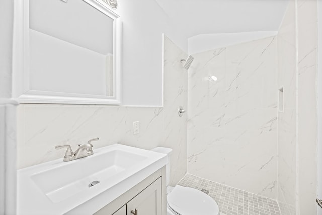 bathroom featuring tasteful backsplash, a tile shower, vanity, tile walls, and toilet