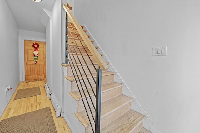 staircase with hardwood / wood-style flooring and a baseboard heating unit