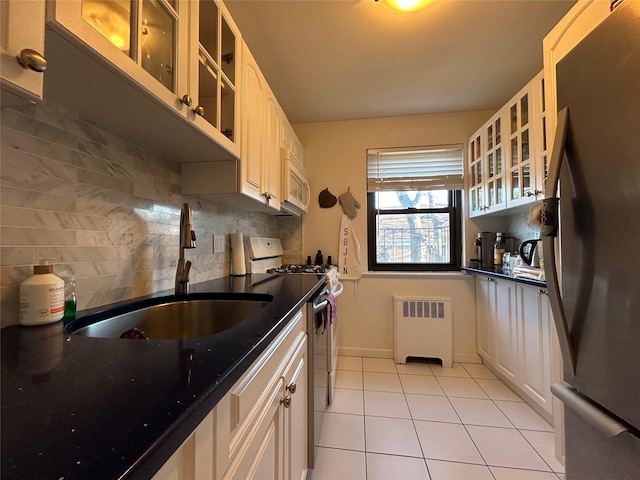 kitchen with radiator, sink, gas range oven, backsplash, and stainless steel fridge