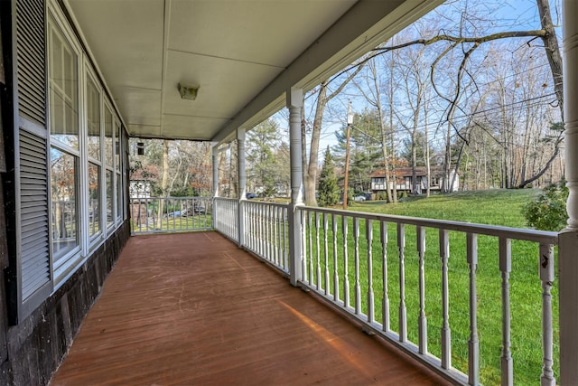 wooden terrace with a lawn and a porch