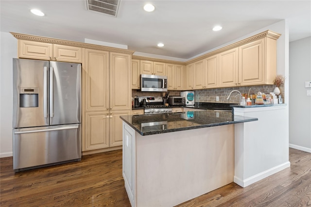 kitchen featuring backsplash, dark stone countertops, stainless steel appliances, and dark wood-type flooring