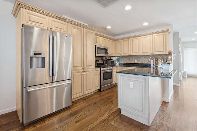 kitchen with backsplash, stainless steel appliances, dark stone counters, and dark wood-type flooring