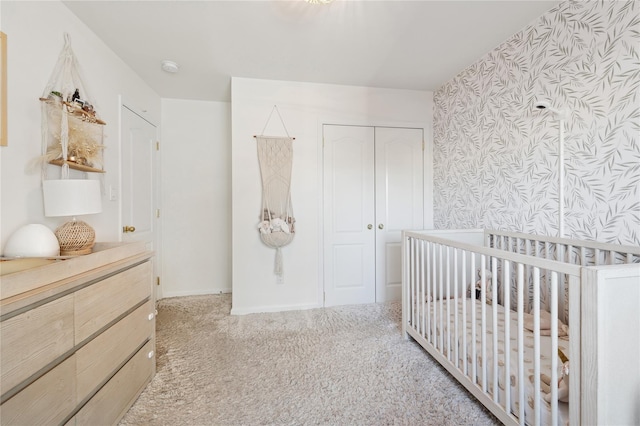 carpeted bedroom featuring a nursery area and a closet