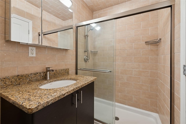 bathroom with vanity, a shower with door, tile walls, and tasteful backsplash