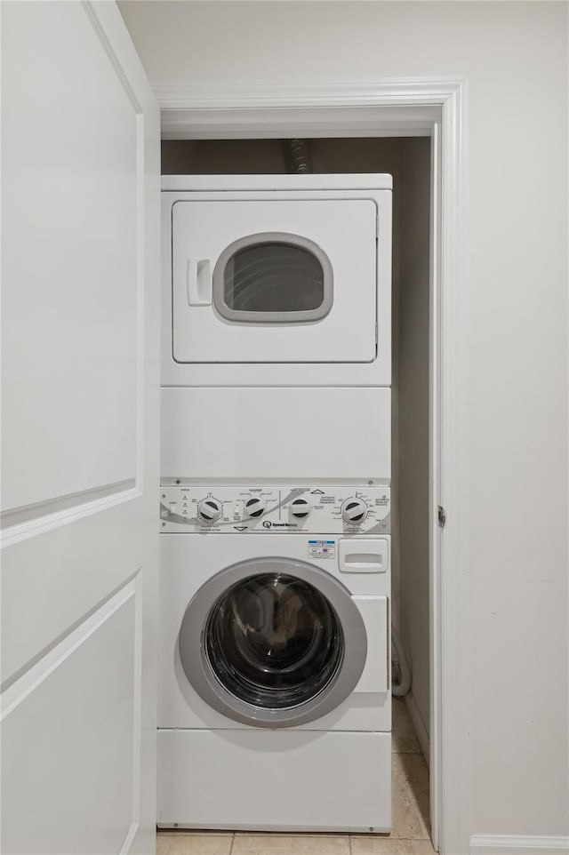 clothes washing area featuring light tile patterned floors and stacked washing maching and dryer