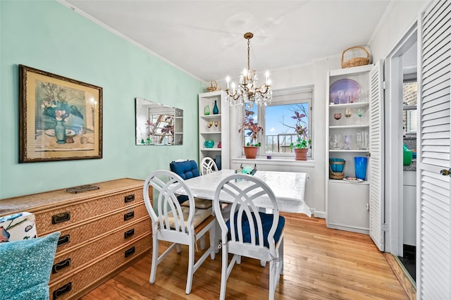 dining space with a notable chandelier, light wood-type flooring, and ornamental molding