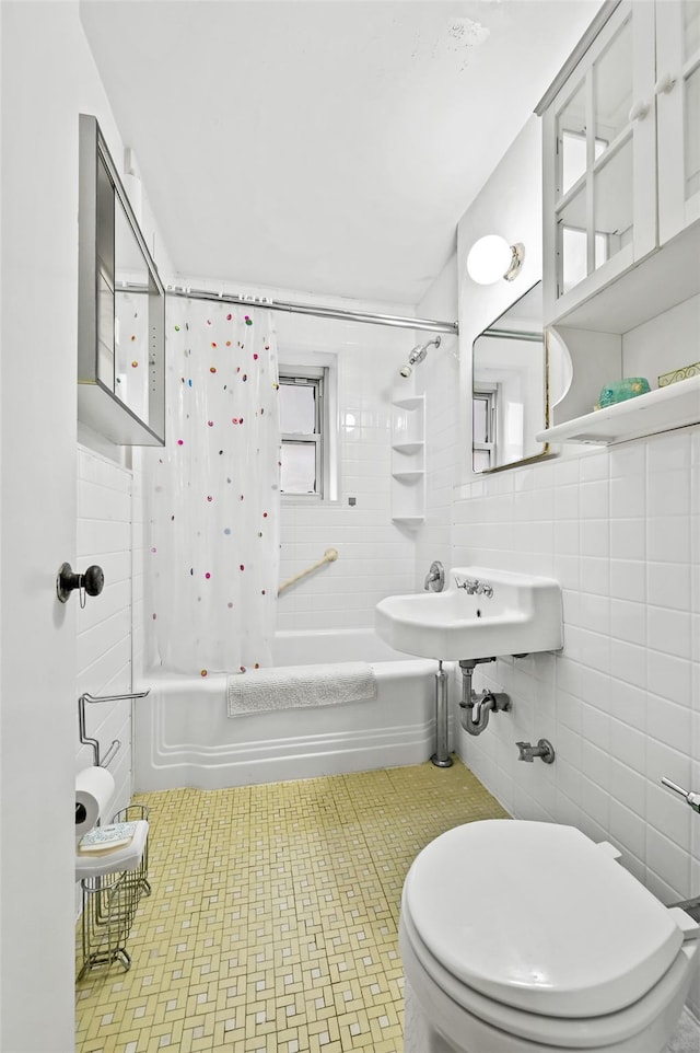 bathroom with shower / tub combo, toilet, and tile walls