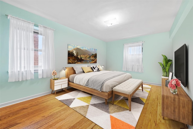 bedroom with hardwood / wood-style floors and multiple windows