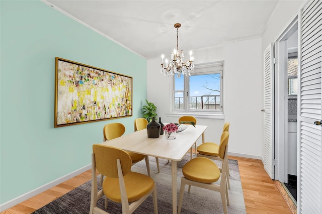 dining area with light wood-type flooring, crown molding, and an inviting chandelier