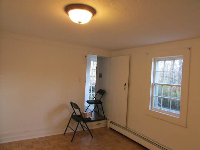 foyer with parquet flooring, a textured ceiling, and a baseboard heating unit