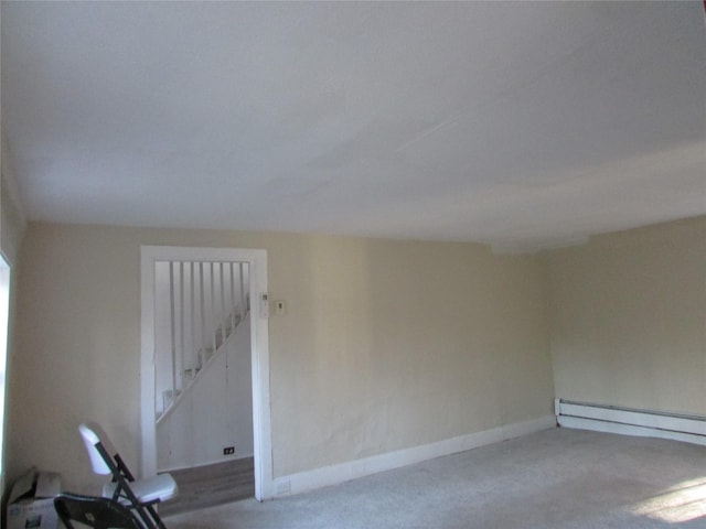 carpeted empty room with a baseboard heating unit