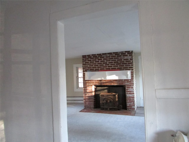 interior space with carpet floors, a wood stove, and a baseboard heating unit