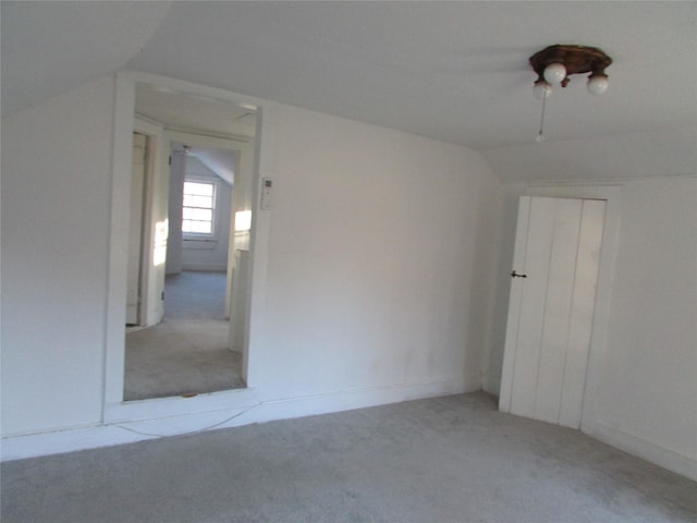 additional living space featuring lofted ceiling and light carpet