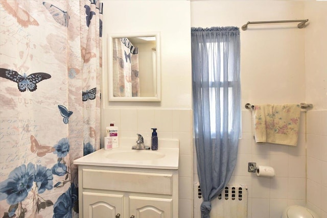 bathroom with vanity, radiator, and tile walls