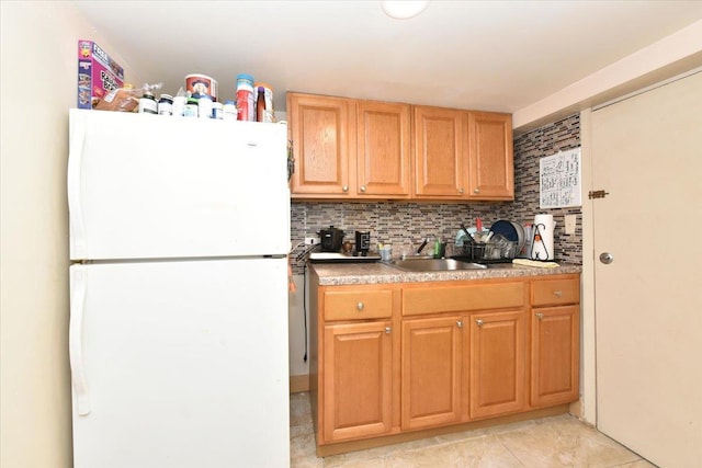 kitchen featuring backsplash, sink, white fridge, and light tile patterned flooring