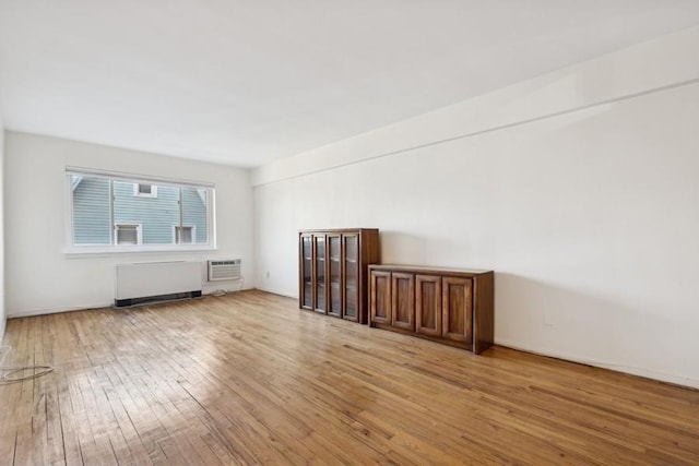 interior space with radiator heating unit, light wood-type flooring, and a wall unit AC