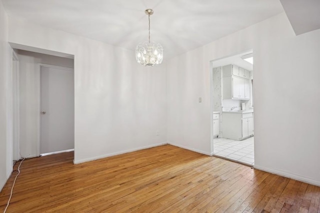 spare room with light wood-type flooring and an inviting chandelier