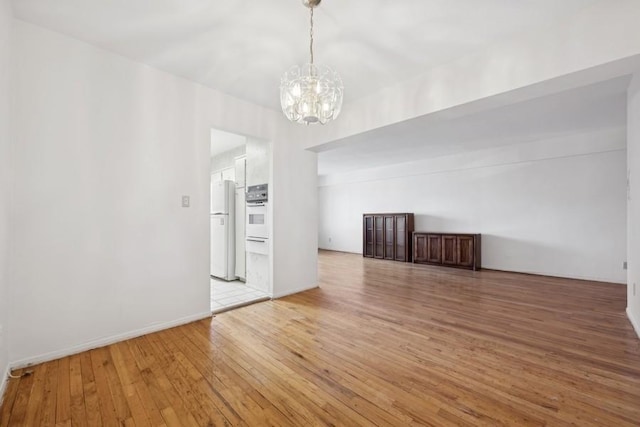 spare room featuring wood-type flooring and a notable chandelier