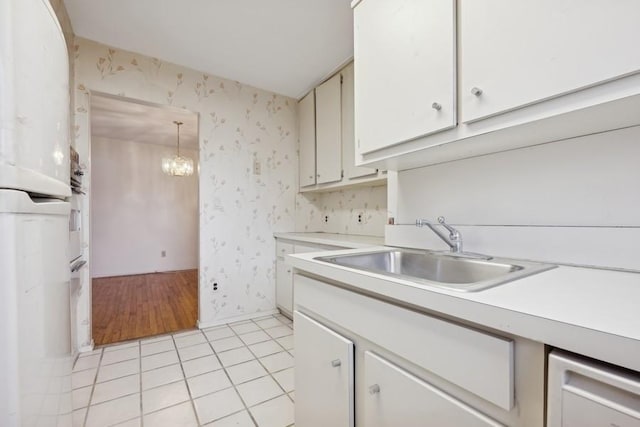 kitchen featuring white cabinetry, an inviting chandelier, sink, hanging light fixtures, and light tile patterned floors