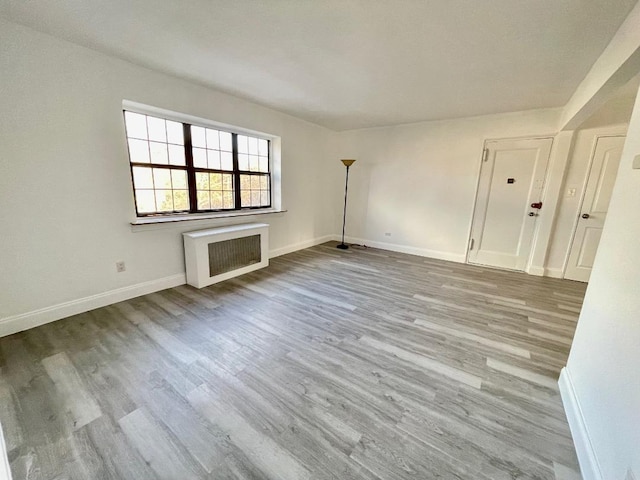 unfurnished living room featuring radiator and light hardwood / wood-style flooring