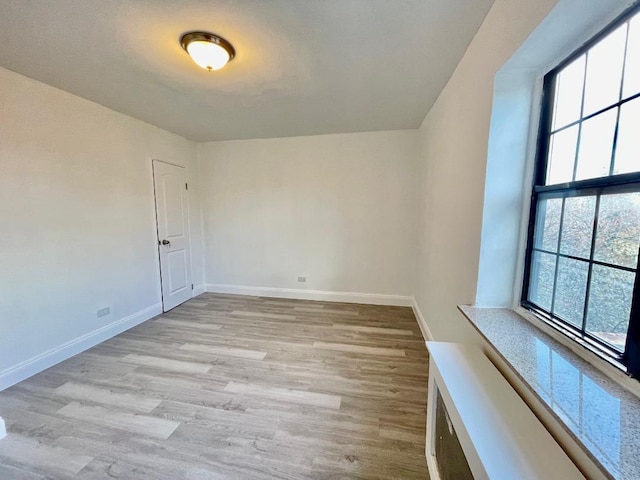 empty room with light hardwood / wood-style floors and a healthy amount of sunlight