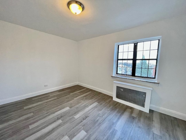 unfurnished living room with heating unit and dark hardwood / wood-style flooring