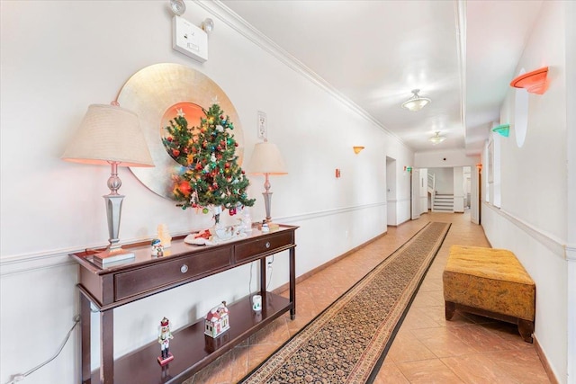 hallway with ornamental molding and light tile patterned floors