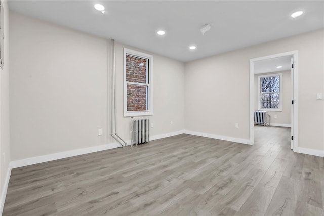 unfurnished room featuring radiator heating unit and light wood-type flooring