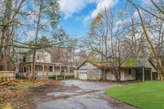 view of front of home featuring covered porch, a garage, and a front yard