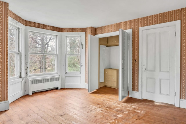 interior space featuring light hardwood / wood-style floors, radiator, and a healthy amount of sunlight