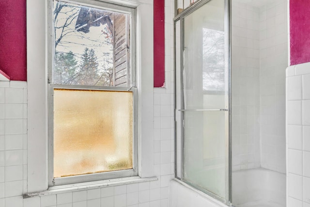 bathroom with bath / shower combo with glass door and a wealth of natural light