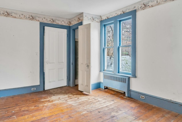 unfurnished bedroom with radiator and hardwood / wood-style floors