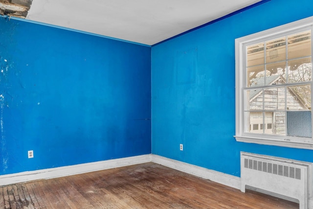 empty room with radiator heating unit and wood-type flooring