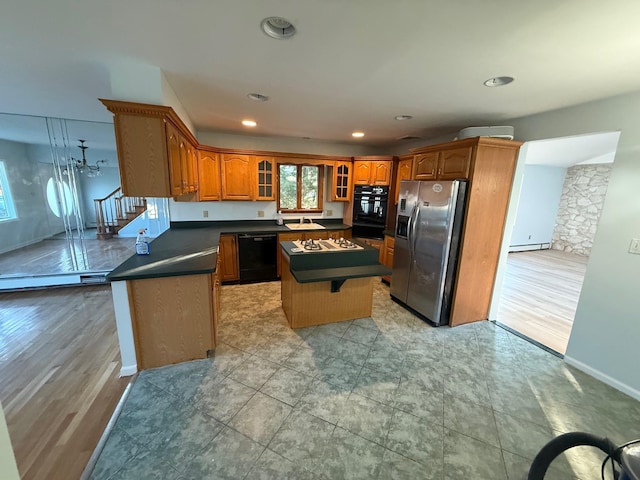 kitchen with a kitchen breakfast bar, black appliances, a baseboard radiator, light hardwood / wood-style flooring, and a center island